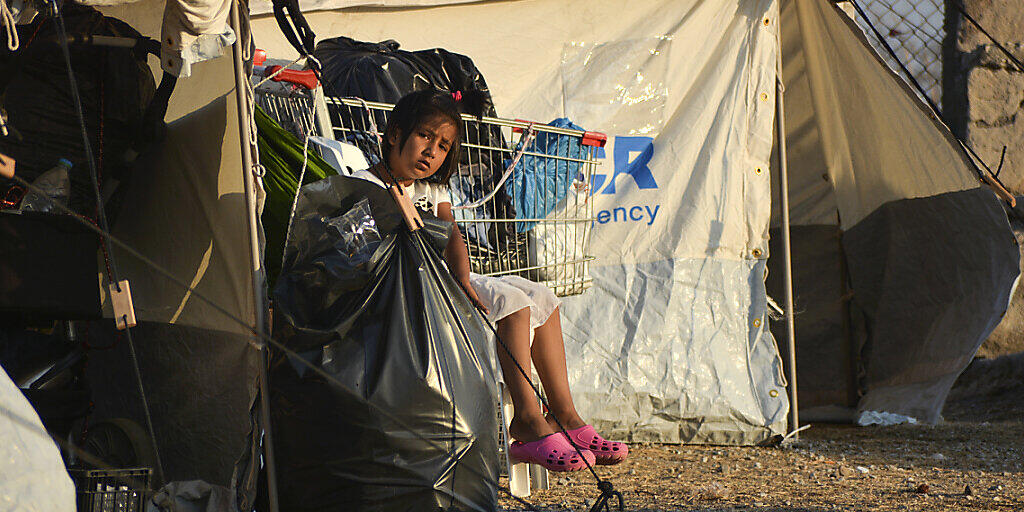 Ein Kind sitzt im neu errichteten temporären Flüchtlingslager in Kara Tepe neben einem Zelt. Auf der griechischen Insel Lesbos sind knapp drei Viertel der 12 000 Migranten aus dem abgebrannten Camp Moria in ein provisorisches Zeltlager gezogen. Foto: Panagiotis Balaskas/AP/dpa