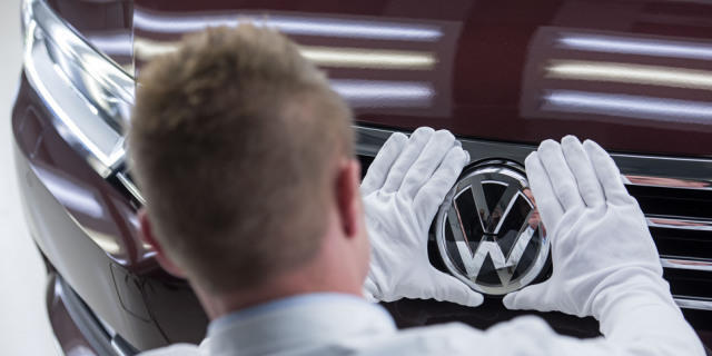 Ein Arbeiter überprüft das Volkswagen-Logo an einem Auto (Archiv)