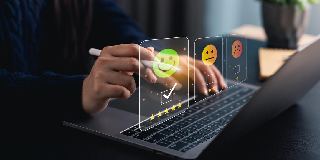 Close-up hand woman interacts with a laptop to express feedback using emotion icons and star ratings, reflecting the importance of customer satisfaction digital workplace.