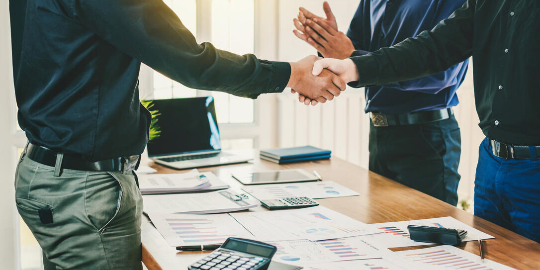 Businessman stand handshake and clapping of appreciation about the success of business at meeting.