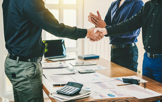 Businessman stand handshake and clapping of appreciation about the success of business at meeting.