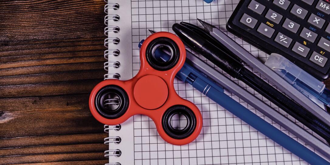 Spinner and different stationeries on wooden desk. Top view