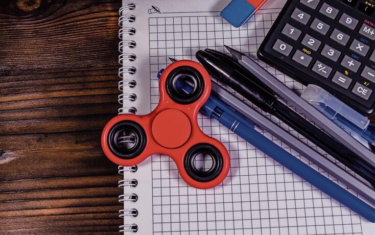 Spinner and different stationeries on wooden desk. Top view