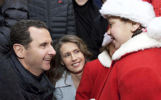 Der syrische Präsident Baschar al-Assad (links) und seine Ehefrau Asma (Mitte) begrüssen als Weihnachtsmänner verkleidete christliche Waisen in Sednaja nördlich von Damaskus (in einer Aufnahme vom Sonntag, wie sie auf der Facebook-Seite des syrischen Präsidialamtes erschien).