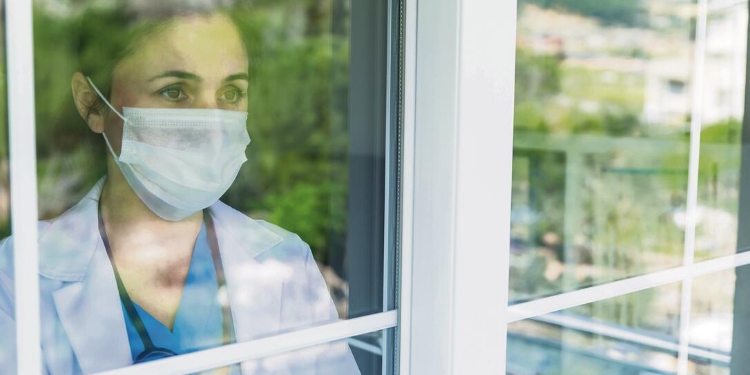 Worried female doctor looking through the hospital window Worried female doctor looking through the hospital window