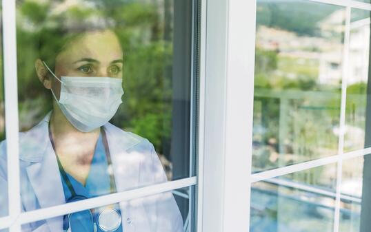 Worried female doctor looking through the hospital window