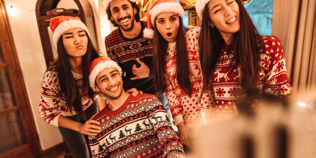 Freunde feiern zusammen Weihnachten im Ugly Sweater.