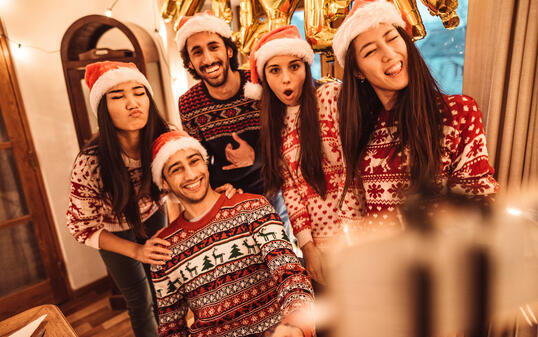 Freunde feiern zusammen Weihnachten im Ugly Sweater.