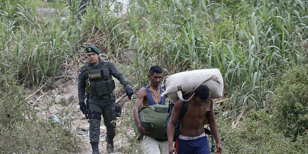Schmuggel als Versorgungsquelle: Ein kolumbianischer Grenzpolizist begleitet zwei Schmuggler aus Venezuela, die bei La Parade illegal die Grenze überquerten.