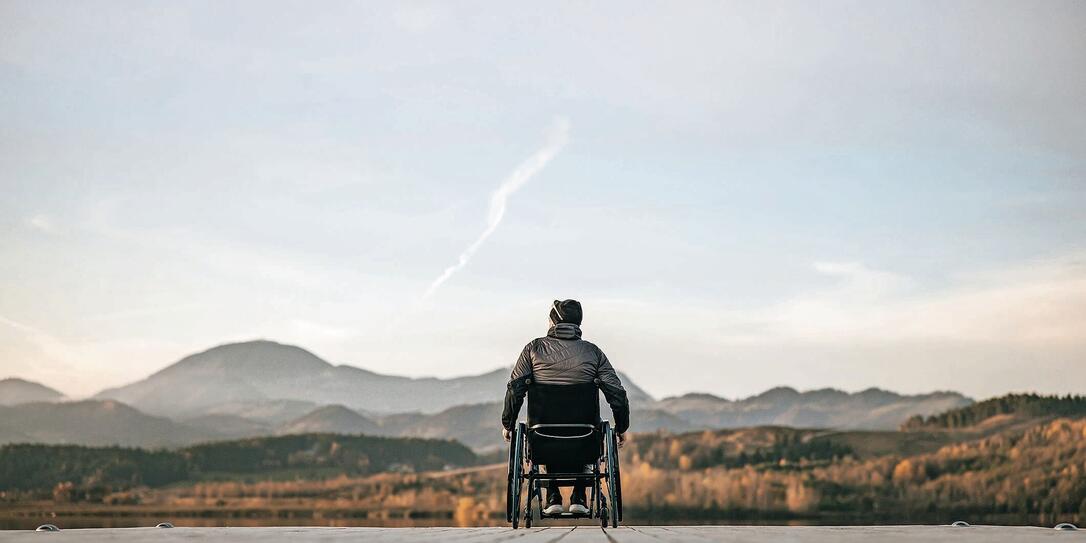 Paraplegic in wheelchair on pier at sunset