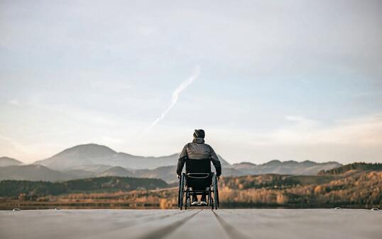 Paraplegic in wheelchair on pier at sunset