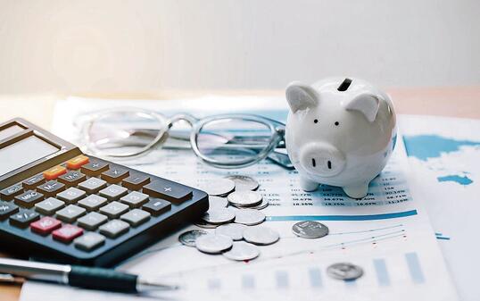 Calculator with text Tax Saving. Calculator, Piggy Bank, coins, business graph and pen on wooden table."Concept saving money for finance accounting