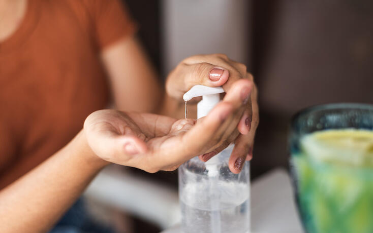 Young woman sanitizing her hands before snack at a restaurant
