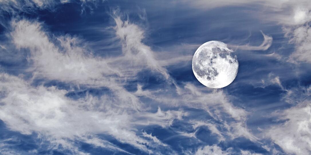 Waning moon on blue sky with cirrus clouds Waning moon on blue sky with cirrus clouds