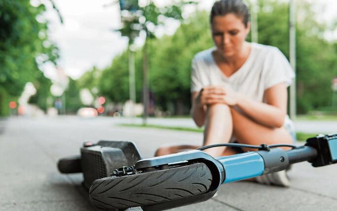 Young woman suffering from knee pain after e-scooter riding accident