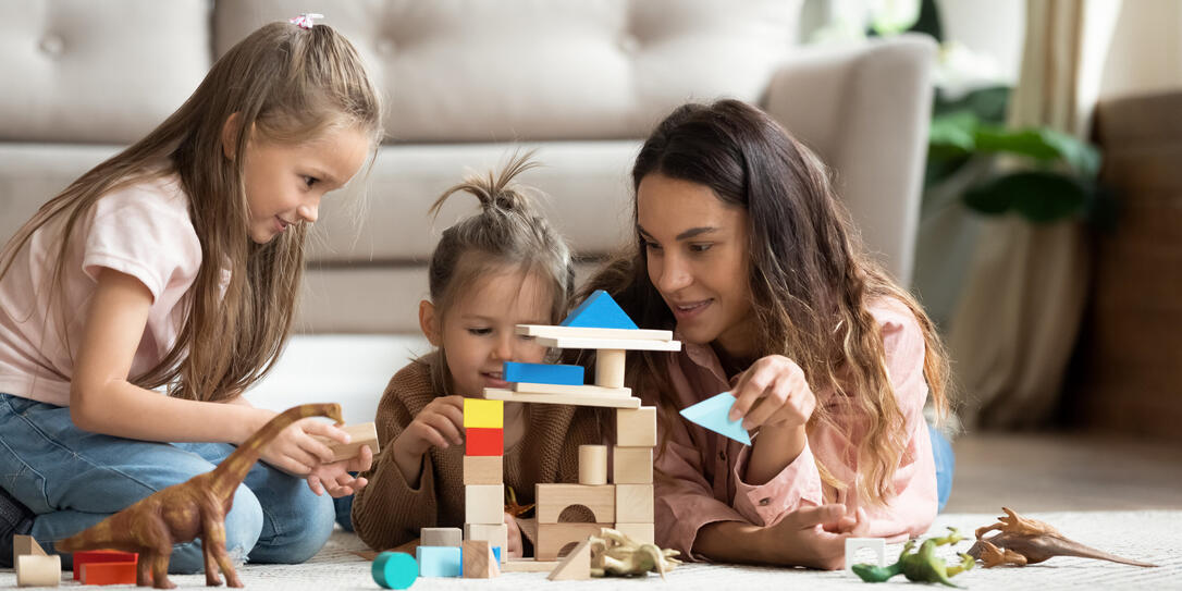Mother play wooden blocks with two little daughters at home