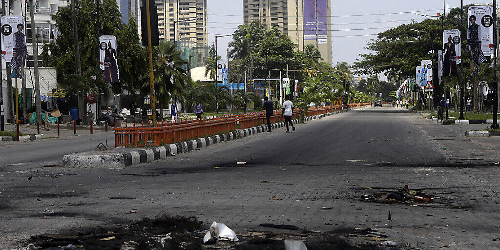 Auf einer sonst leeren Straße liegen die Überreste von abgebrannten Straßenblockaden. Nach einem Blutbad bei einer Kundgebung gegen Polizeiübergriffe gehen die Proteste im westafrikanischen Nigeria unvermindert weiter. Foto: Sunday Alamba/AP/dpa