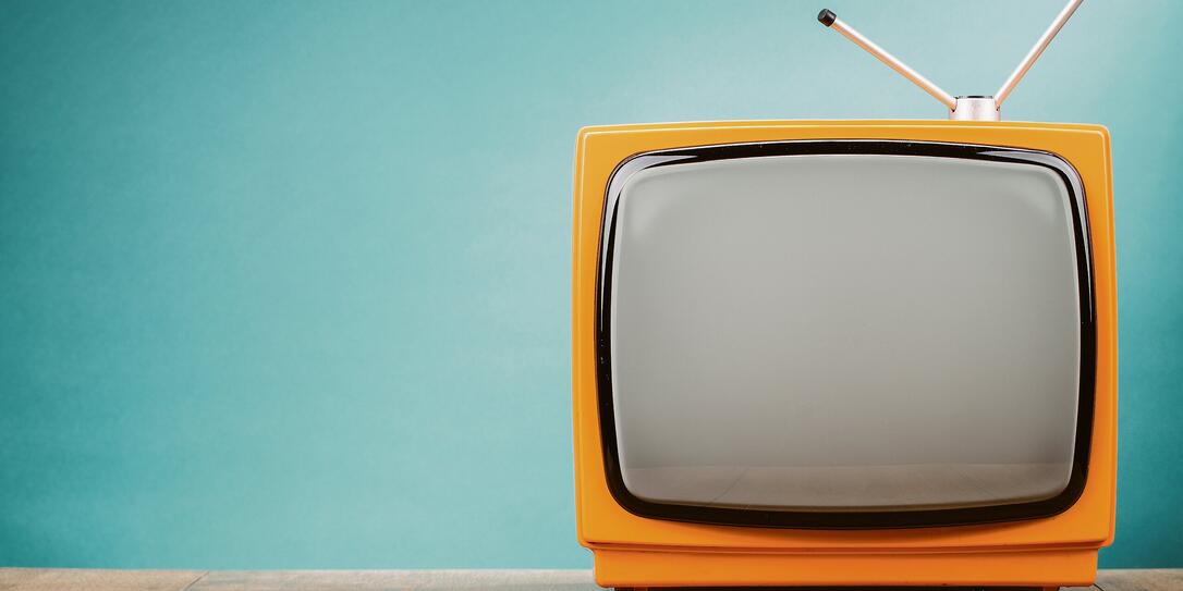 Retro old orange TV receiver on table front gradient aquamarine wall background. Vintage style filtered photo Retro old orange TV receiver on table front gradient aquamarine wall background. Vintage style filtered photo