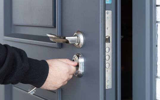 Man opens the lock of the front door of a private house.