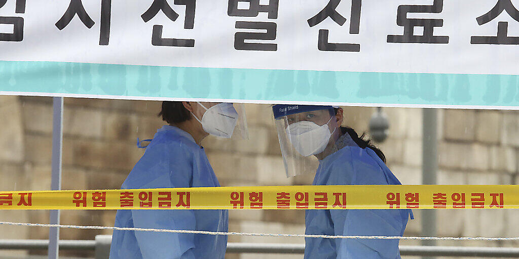 Medizinische Mitarbeiterinnen in Schutzkleidung stehen in einer Einrichtung für Covid-19-Tests in Südkorea. Foto: Ahn Young-Joon/AP/dpa