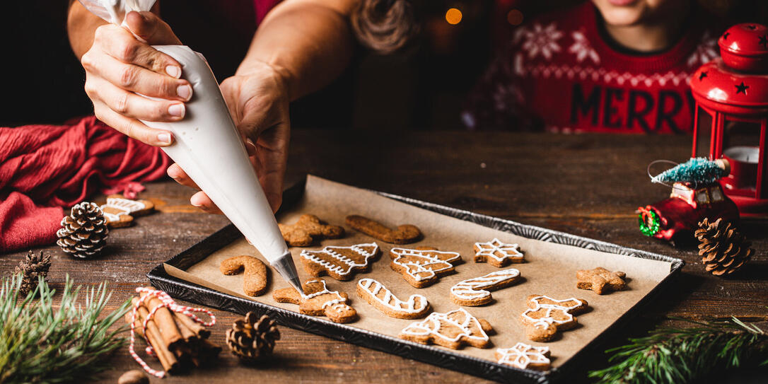 Woman icing gingerbread christmas cookie by son in kitchen Woman icing gingerbread christmas cookie by son in kitchen