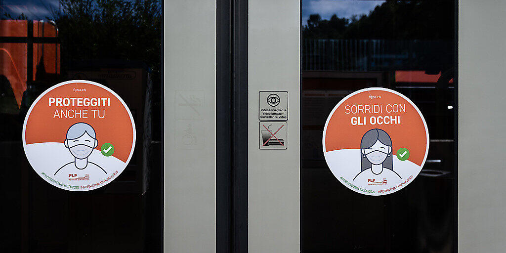 Hinweisschilder auf die Maskenpflicht an den Türen eines Lokalzugs der Lugano-Ponte-Tresa-Bahn FLP.