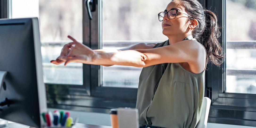 Tired businesswoman stretching body for relaxing while working with computer in the office.