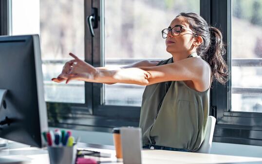 Tired businesswoman stretching body for relaxing while working with computer in the office.