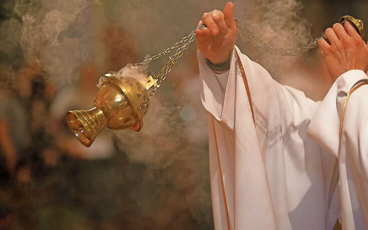 Priest incenses the altar with incense during Holy Mass