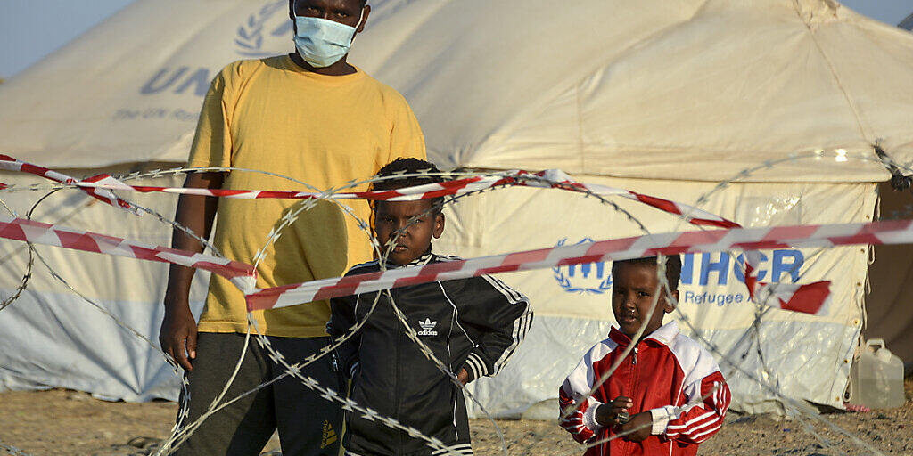 Ein Migrant steht mit zwei Kindern vor einem Stacheldrahtzaun im neu errichteten temporären Flüchtlingslager in Kara Tepe. Foto: Panagiotis Balaskas/AP/dpa Ein Migrant steht mit zwei Kindern vor einem Stacheldrahtzaun im neu errichteten temporären Flüchtlingslager in Kara Tepe. Foto: Panagiotis Balaskas/AP/dpa