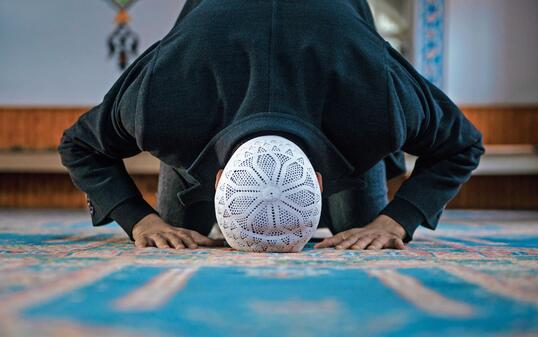 Close-up shot of a Muslim young man worshiping in a mosque