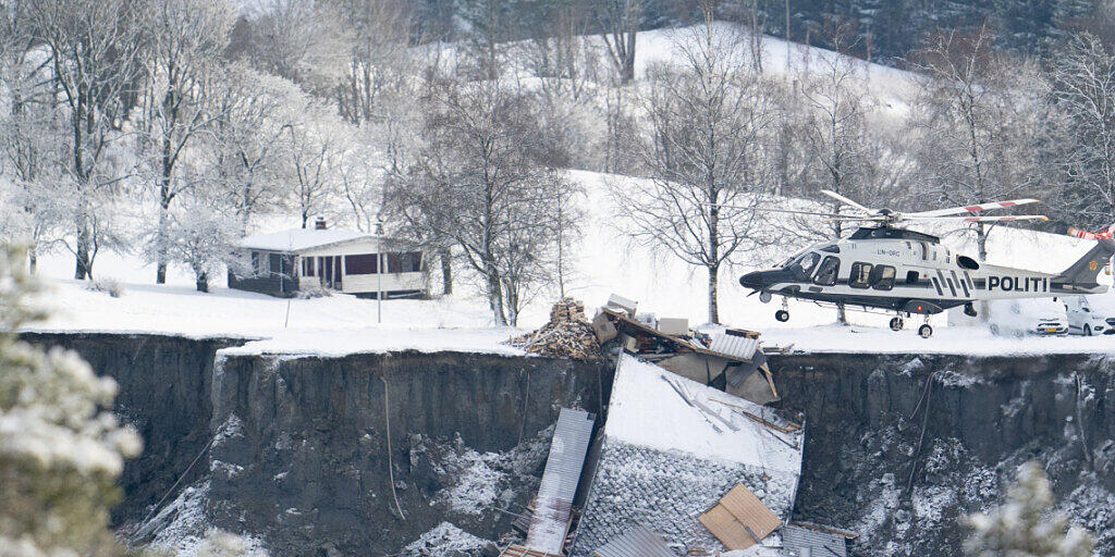 dpatopbilder - Ein Helikopter fliegt über die Stelle, an der ein Erdrutsch zahlreiche Häuser in die Tiefe gerissen oder zerstört hat. Foto: Fredrik Hagen/NTB/dpa