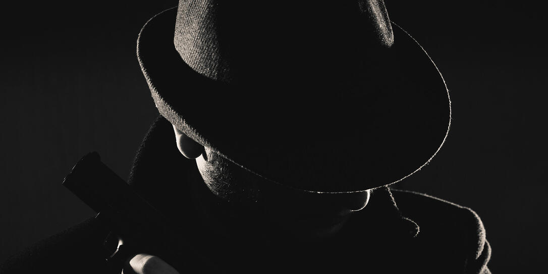 Retro man in coat and hat holding a gun