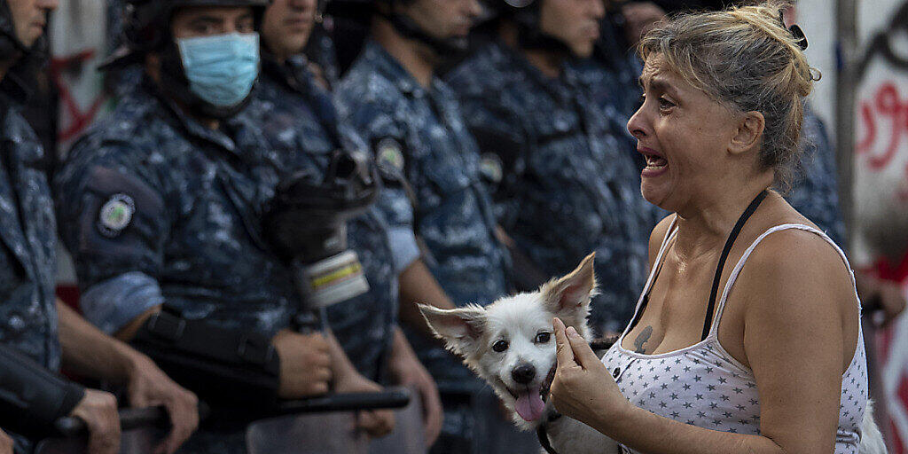 Eine Teilnehmerin eines regierungskritischen Protestes vor einer Kette Polizisten. Foto: Hassan Ammar/AP/dpa