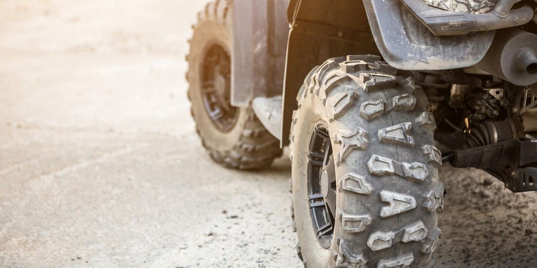 Close-up tail view of ATV quad bike. Dirty whell of AWD all-terrain vehicle. Travel and adventure concept.Copyspace.Toned