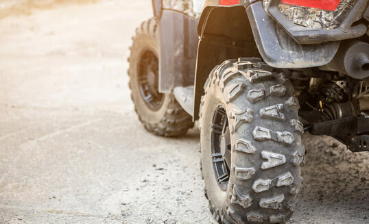 Close-up tail view of ATV quad bike. Dirty whell of AWD all-terrain vehicle. Travel and adventure concept.Copyspace.Toned