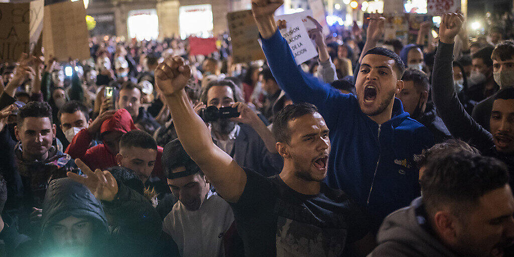 Demonstranten rufen Parolen gegen die Regierung bei einem Protest gegen die neuen Anti-Corona-Massnahmen. Bei dem Protest kam es zu Zusammenstößen mit der Polizei. Die Demonstranten protestierten gegen die Schließung von Bars, Restaurants und anderen Geschäften inmitten der Corona-Pandemie. Foto: Emilio Morenatti/AP/dpa Demonstranten rufen Parolen gegen die Regierung bei einem Protest gegen die neuen Anti-Corona-Massnahmen. Bei dem Protest kam es zu Zusammenstößen mit der Polizei. Die Demonstranten protestierten gegen die Schließung von Bars, Restaurants und anderen Geschäften inmitten der Corona-Pandemie. Foto: Emilio Morenatti/AP/dpa