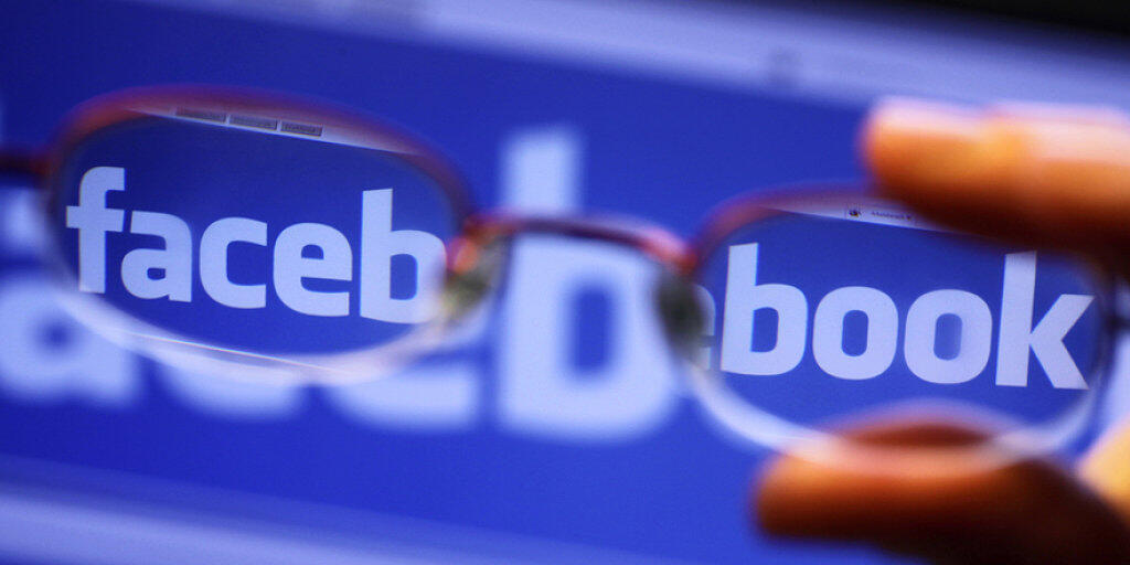 Durch die Gläser einer Brille ist der Schriftzug von Facebook auf einem Laptop zu sehen. (Symbolbild)