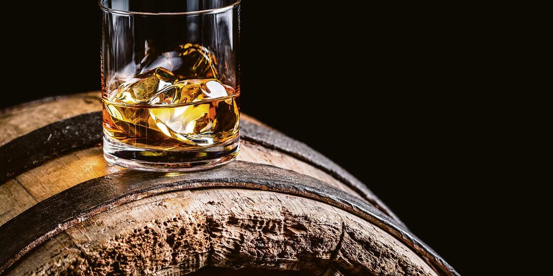 Glass of whisky with ice on old wooden barrel Glass of whisky with ice on old wooden barrel
