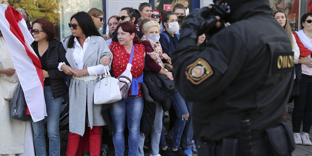 Frauen mit alten belarussischen Nationalflaggen stehen bei einer Demonstration gegen die Wahlergebnisse in Belarus neben einem Polizeibeamten. Foto: Uncredited/TUT.by/dpa Frauen mit alten belarussischen Nationalflaggen stehen bei einer Demonstration gegen die Wahlergebnisse in Belarus neben einem Polizeibeamten. Foto: Uncredited/TUT.by/dpa