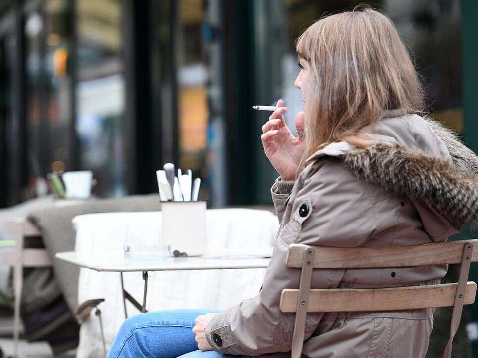 Frau mit Zigarette vor einem Restaurant in Wien.