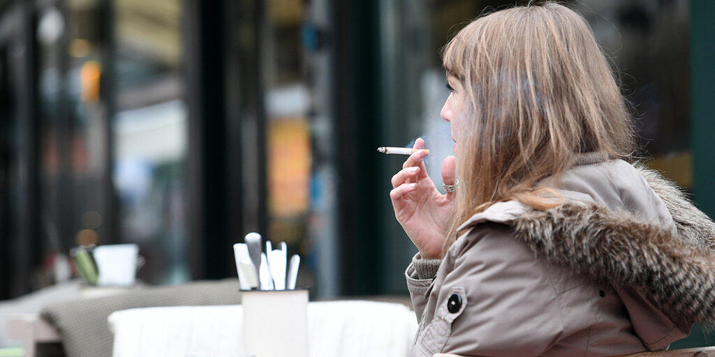 Frau mit Zigarette vor einem Restaurant in Wien.