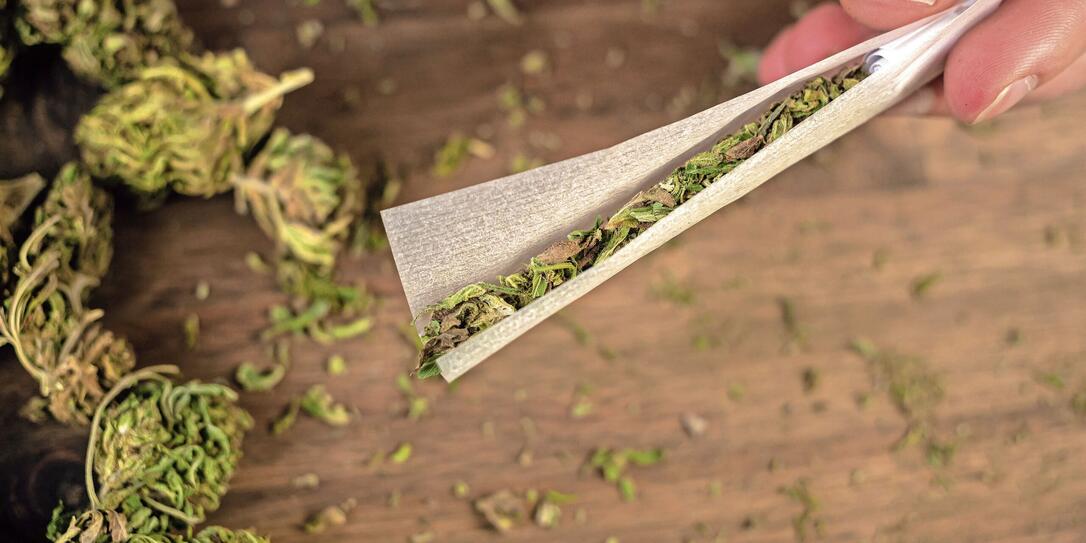 Male hands rolling marijuana joint