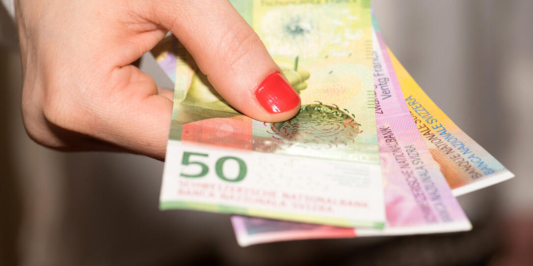 A woman holds Swiss franc banknotes in her hand A woman holds Swiss franc banknotes in her hand