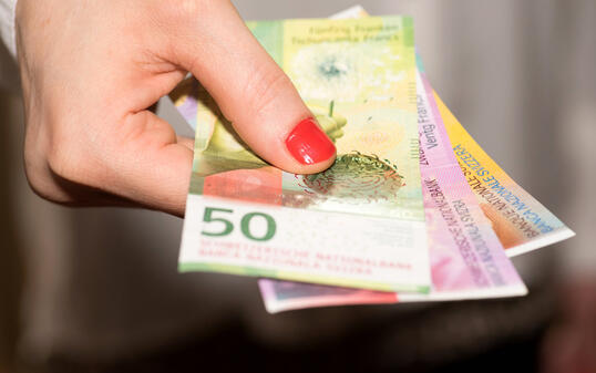A woman holds Swiss franc banknotes in her hand