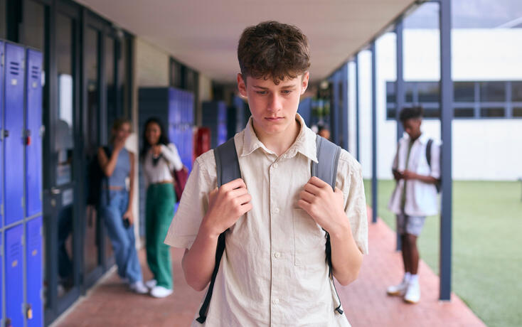 Unhappy Teenage Boy Outdoors At High School Being Teased Or Bullied