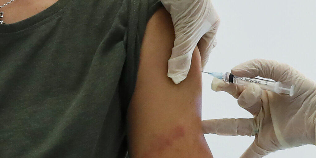 Ein Mitarbeiter des Gesundheitswesens führt in Moskau eine Impfung mit dem Corona-Impfstoff «Sputnik V» durch. Foto: Pavel Golovkin/AP/dpa