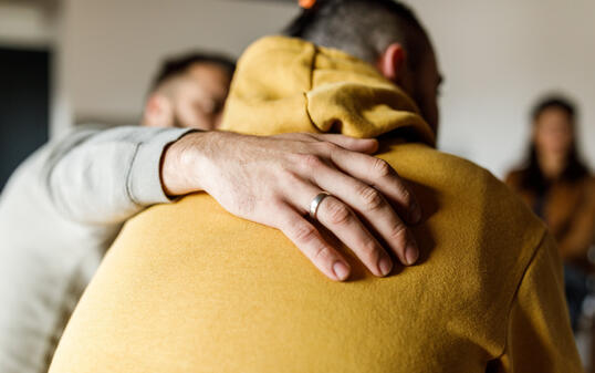 Man embracing his friend who is sharing his story at the group therapy session