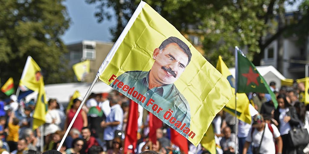 Eine Demonstrantin hält in Köln eine Öcalan-Flagge hoch.