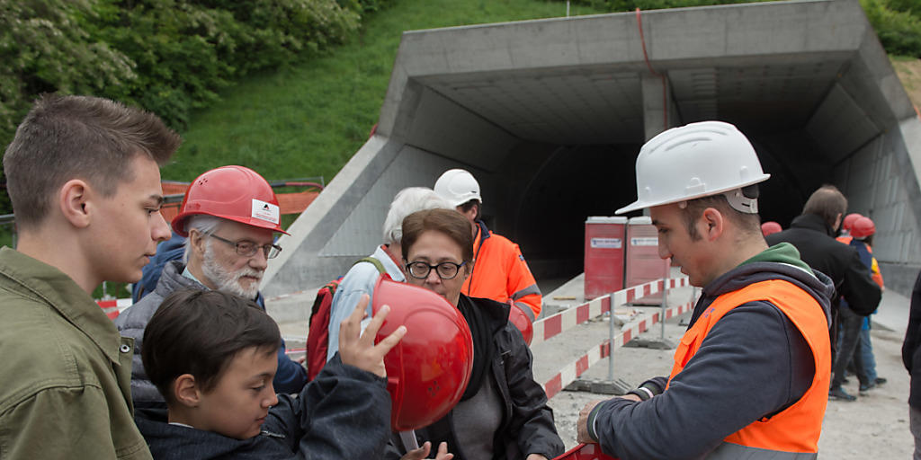 Besucher mit Schutzhelmen machen sich am Tunnelportal des Ceneri-Basistunnels bereit für die Besichtigung. Besucher mit Schutzhelmen machen sich am Tunnelportal des Ceneri-Basistunnels bereit für die Besichtigung.
